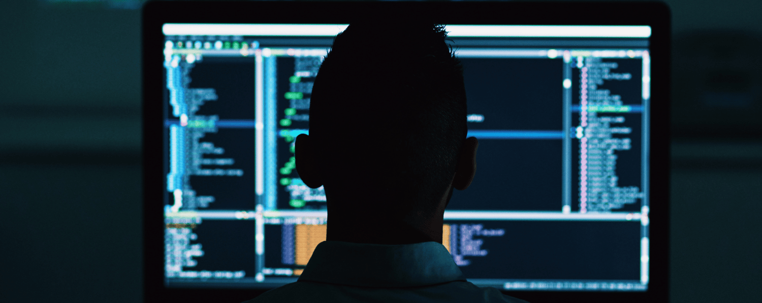 Silhouette of Developer Facing Screen with Code, Representing Headless Commerce Development